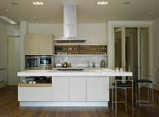 A kitchen in an open-plan living room with an island counter and a central extractor hood