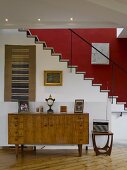 Retro-style cabinet in front of staircase with red-painted wall