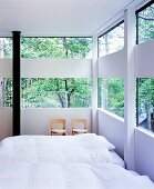 Bedroom in house made of glass and wood elements in forest