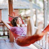 Young woman lying in hammock on terrace