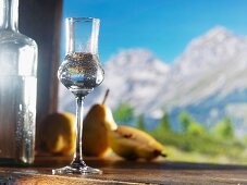 A glass of William's pear schnapps against an alpine backdrop