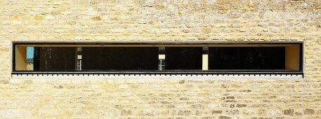 Schmaler horizontaler Fensterschlitz in Natursteinfassade