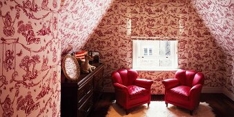 Attic room with red armchairs and wallpaper with erotic pattern