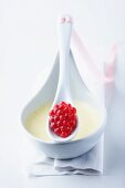 A bowl of white mousse with a raspberry sweet on a spoon