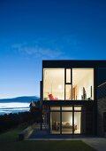 Illuminated house with glass walls at dusk