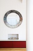 Grosser runder Spiegel hängt über einem Einbaukamin