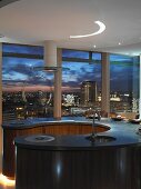Circular kitchen unit in penthouse apartment with panoramic view of city skyline