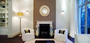 Covered armchairs and retro standard lamp in front of open fireplace