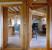 View through adjacent wooden doors into country-style kitchen and rustic dining room with fireplace