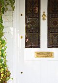 White, antique front door with stained glass windows and brass letterbox