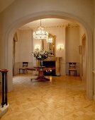 Villa foyer with parquet floor and view of antique table through rounded arch