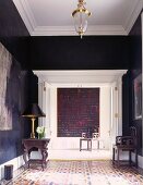 Antique furniture in corner of elegant, traditional foyer with dark walls and white stucco ceiling