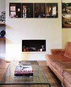 Coffee table made from single sheet of curved glass and leather sofa in front of open fireplace