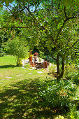 Sonniger Terrassenplatz im Garten mit Tisch und Stühlen