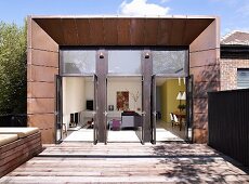 Modernes Wohnhaus mit offen stehenden Glastüren und Holzterrasse