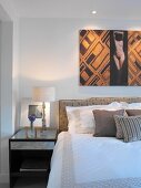 Modern picture above double bed with upholstered headboard - mix of styles and patterns in bedroom