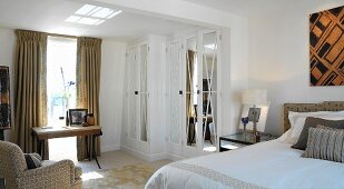 Comfortable bedroom with desk under window and fitted wardrobe with mirrored doors