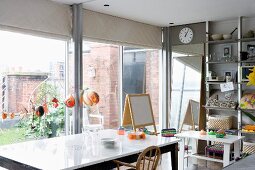 Dining area with simple, modern furniture and children's playthings in front of glass wall leading to courtyard garden
