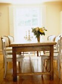 Rustic dining table in natural wood with a mixture of chair styles and bouquet