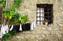 Hauswand mit vergittertem Fenster und aufgehängter Wäsche