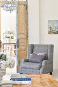Grey, upholstered armchair in corner of room next to open interior door