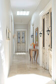 Narrow hallway in traditional country house with glass panels in doors and rustic console table