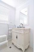 White-painted, antique cabinet in corner of white, renovated bathroom