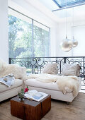 Comfortable sofa corner on bright gallery in house with solid wood floorboards and panoramic windows