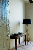 Open interior door showing view of simple console table next to designer standard lamp