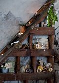 Christmas decorations on dark-stained wooden shelves under stairs