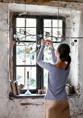 Small decorations hanging from beech branch in front of window