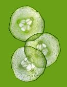 Three slices of cucumber on a green surface