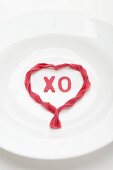 White plate with heart made of red pasta