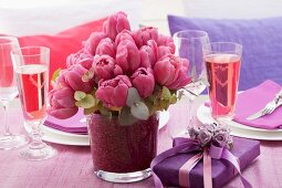 Festlich gedeckter Tisch mit Tulpen, Geschenk und Rose-Sekt