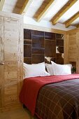 Modern bedroom with rustic wooden wardrobe and panels of animal skin on wall
