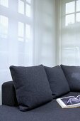 Grey sofa cushions to match sofa against transparent curtain in corner of living room