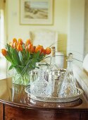 Crystal decanters on silver tray next to bouquet of orange tulips