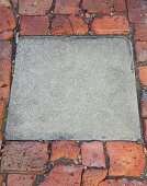 Square concrete block combined with uneven brick pavement