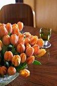 Orangefarbener Tulpenstrauss auf Tisch