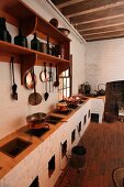 Rustikale Küche mit mehreren Feuerstellen in gemauerter Küchenzeile und Kochgeschirr aus Kupfer