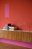 Wooden sideboard against wall in different shades of red and pink