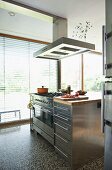 Stainless steel kitchen block with extractor hood in front of terrace windows