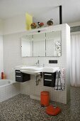 Sink and mirror on white tiled partition in bathroom with terrazzo floor