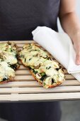 Woman serving bread pizza with mushroom, courgette and cheese