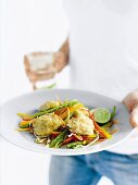 A person holding a plate of vegetables and tofu