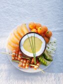 Prawn kebabs with fruit and melon sauce in a coconut shell