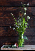 White onion and coriander flowers in preserving jar against rustic wooden wall