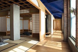 Meditation room with open, Japanese-style sliding wall panels in industrial hall with blue-painted ceiling