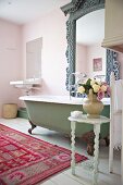 Wohnliches Badezimmer im Shabby-Stil mit buntem Teppich und imposantem Spiegel über antiker Badewanne