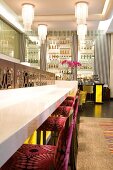 Bar stools with purple floral upholstery at counter in foyer with black and white striped wallpaper